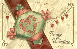 A green and red pillow with a wreath in shape of a heart over a red sash
