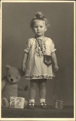 Very Young Girl in Embroidered Dress with Teddy Bear and Book Very Young Girl in Embroidered Dress with Teddy Bear and Book
