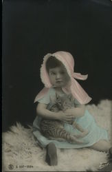 Girl in pink bonnet & blue dress holding cat Girl in pink bonnet & blue dress holding cat