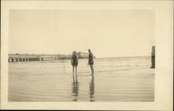 Men on Beach near Pier Men on Beach near Pier