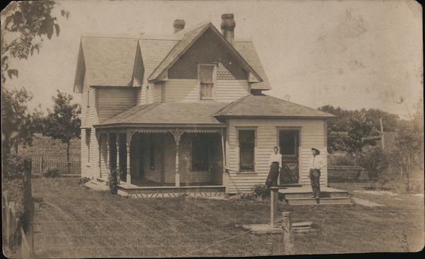 Farmhouse, A man and a woman stand on the steps of a large home in summer time