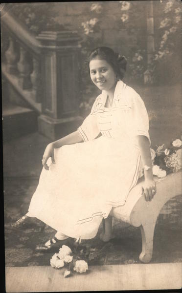 A pretty woman in a dress sits smiling with flowers at her feet Philippines