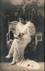 Woman in elegant dress sitting on bench holding flowers Postcard
