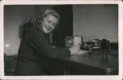 a woman smiling while writing at a desk Postcard