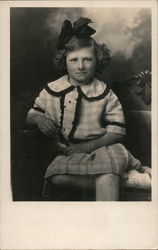 Young girl sitting on loveseat. Postcard