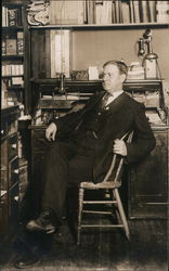 Man in Suit Posing in front of a Desk Postcard