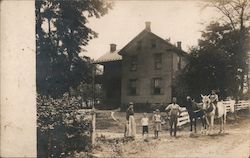 Family Standing at Fence in front of House with a Horse Postcard