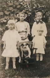 Family photo of four children and a dog. Postcard
