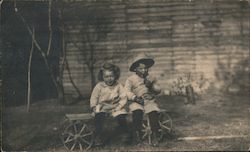 Two Cute Kids Sitting on Old Cart Postcard
