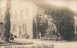 Woman Walking Bicycle in Front of Large Building Postcard