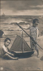 Boys playing with a boat on the beach Postcard
