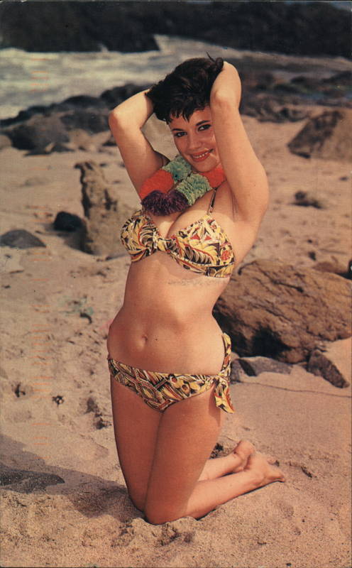 Woman with short hair and a lei posing on the beach while wearing a bikini