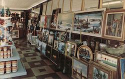 A color photograph of the inside of a store. On the shelves you see cans, kicknacks, and paintings. Postcard