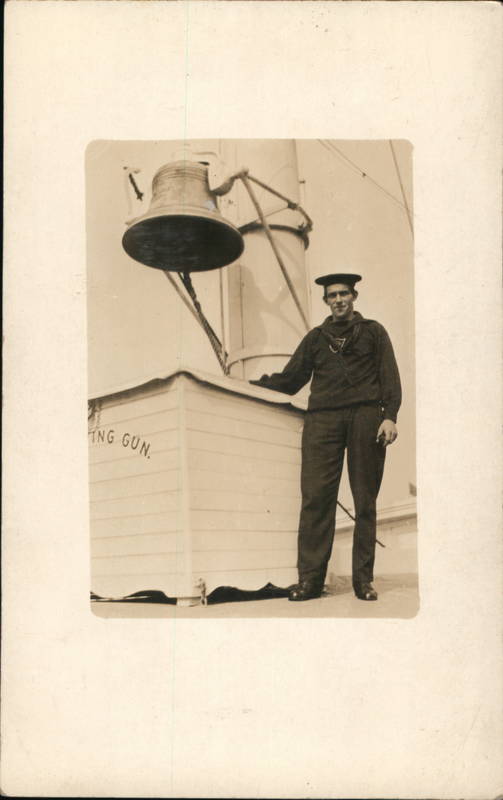 uniformed man standing next to a large bell Navy