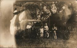 A Man, 2 Women and a Boy Posing in Front of a Car Postcard
