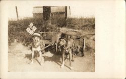 Two Dogs Wearing Hats and Glasses and Pulling Wheeled Carts Postcard