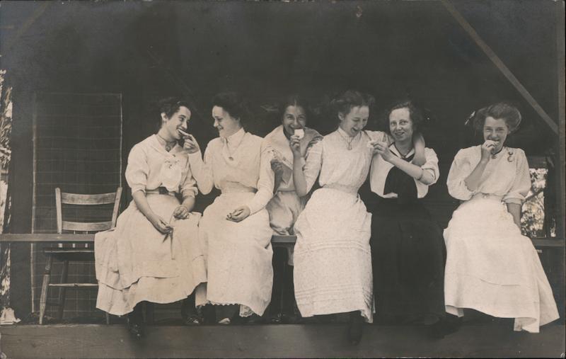 Women in dresses eating cookies.