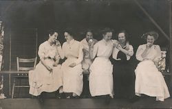 Women in dresses eating cookies. Postcard