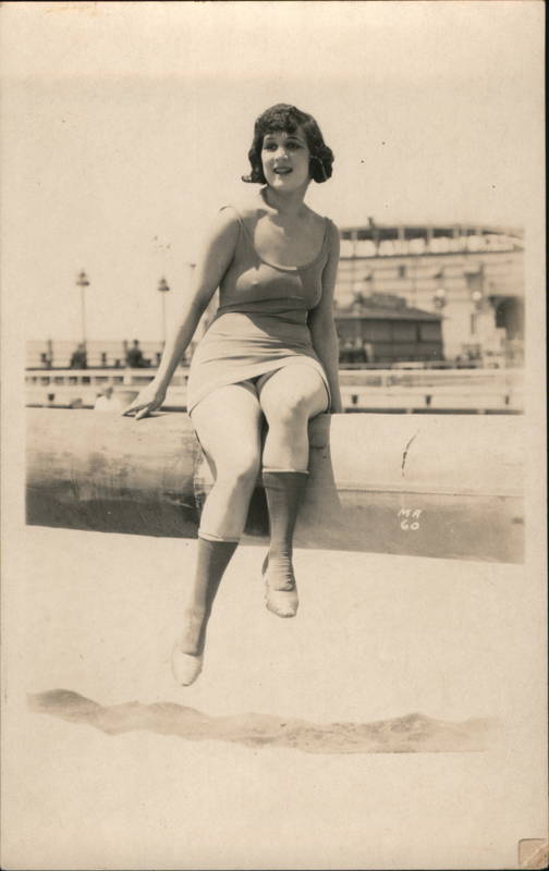 Flapper Woman in dress sitting on log on the beach