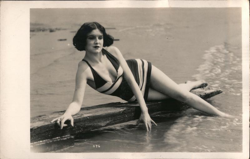 Flapper Woman in Bathing Suit Laying on Rock in Surf