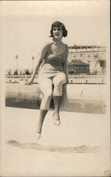 Woman in dress sitting on log on the beach Postcard