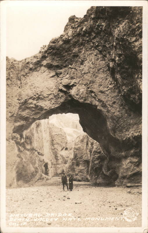 Couple standing below a natural stone arch Death Valley California