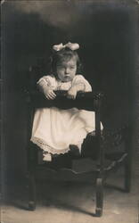 Young Girl with Bow in Wooden Chair Postcard