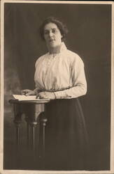 Woman Holding Papers at Table Postcard