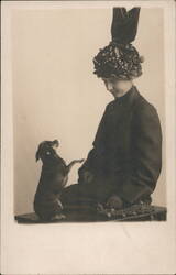 Woman in Embellished Hat Posing with Standing Small Dog Postcard