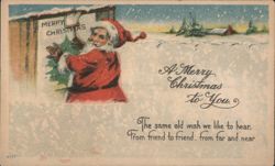 Santa Claus Hanging Merry Christmas Sign in Snowy Landscape Postcard