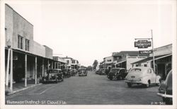 Business District Street Scene with Vintage Cars and Shops Postcard