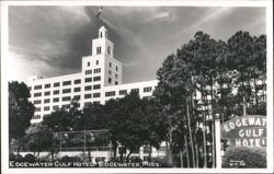 Edgewater Gulf Hotel with prominent tower, flag, and surrounding trees Postcard