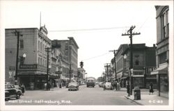 Main Street with Woolworth, Grand Home, businesses, cars, and pedestrians Postcard