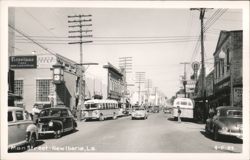 Main Street with Firestone, Drugs signs, cars, and buses Postcard