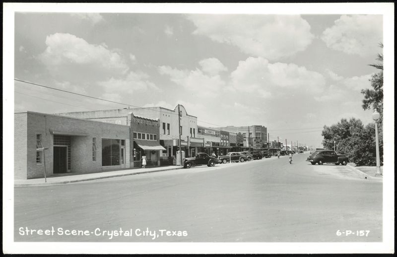 Downtown street scene with businesses and parked cars Crystal City Texas