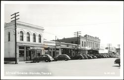 Downtown Street Scene with Stores and Parked Cars Postcard