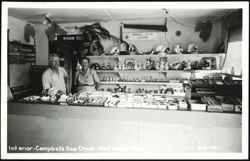 Interior of Campbell's Sea Chest store with two clerks Postcard