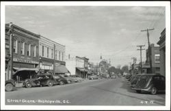 Downtown Street Scene with Parked Cars and Businesses Postcard