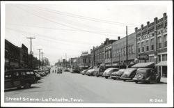 Downtown Street Scene with Parked Cars and Storefronts Postcard