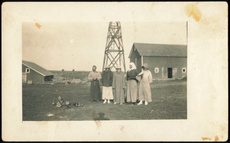 Five Women Standing in Front of Farm Buildings and Windmill