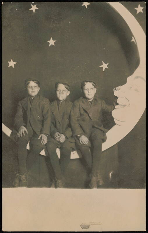 Three Boys Sitting on a Crescent Paper Moon Moons