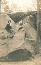 Woman and Dog Sitting on Large Rock Formation Postcard