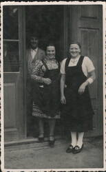 Three People in Doorway, Two Women in Aprons, Man in Hat Postcard