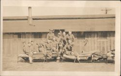 Group of Soldiers Posing with Beds in Front of Barracks Postcard