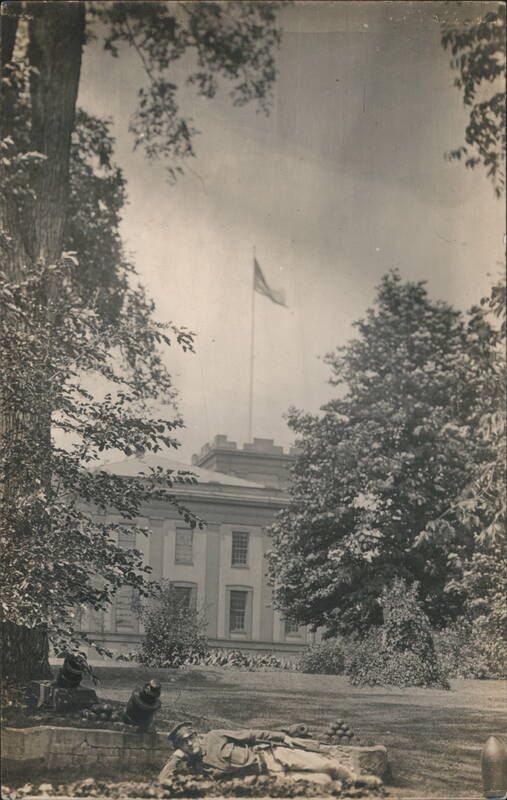Uniformed Soldier Reclining by Mortars on Government Building Grounds