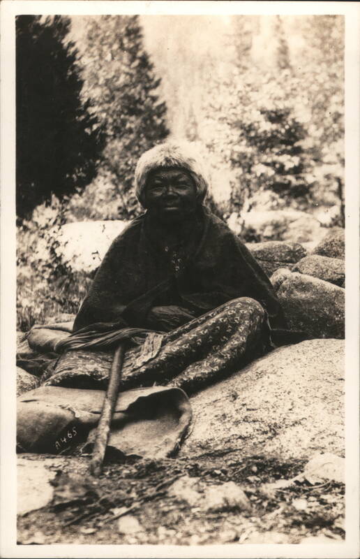 Elderly Native American Woman Seated on Rocks with Staff