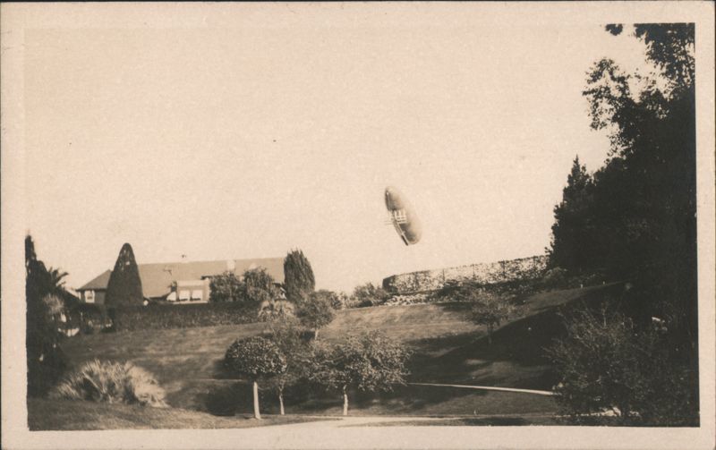 Early Dirigible Airship Flying Over Hillside Estate