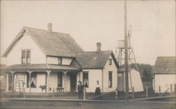 Couple Standing Outside White Farmhouse with Windmill Postcard