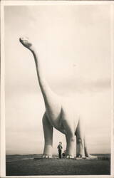 Giant Dinosaur Statue with Person Standing Beneath Postcard
