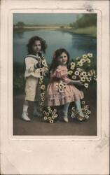 Two Children in Sailor Suit and Pink Dress with Daisies by a River Postcard